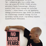 Mężczyzna w czarnej koszulce z napisem NO MORE FEARS trzyma plakat z tym samym hasłem, wspierając QueerMuzeum Warszawa.