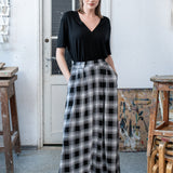 Czarna bluzka z dekoltem w szpic i długie spodnie w czarno-białą kratę, stylowy strój na co dzień