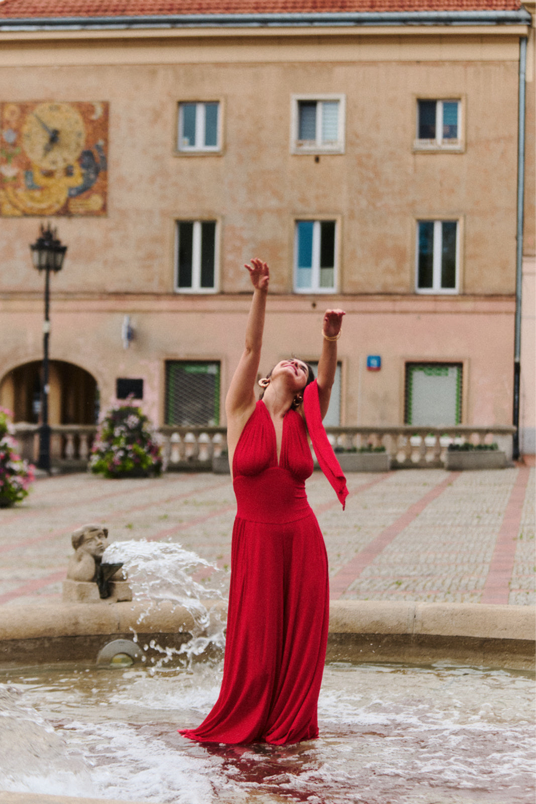 Kobieta w czerwonej sukience wieczorowej stojąca w fontannie, stylowa moda polska, self-care fashion