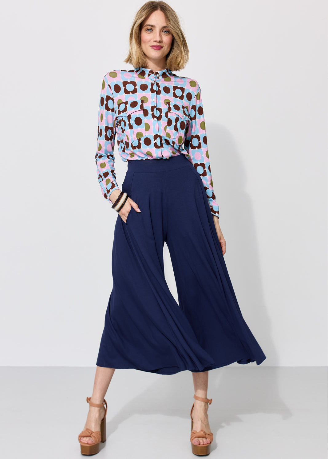 Kobieta w kolorowej koszuli w kwiaty i granatowych spodniach typu culottes, stylowa moda damska