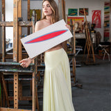 Kobieta w żółtej sukience trzyma obraz w artystycznym atelier, stylowy i wygodny strój