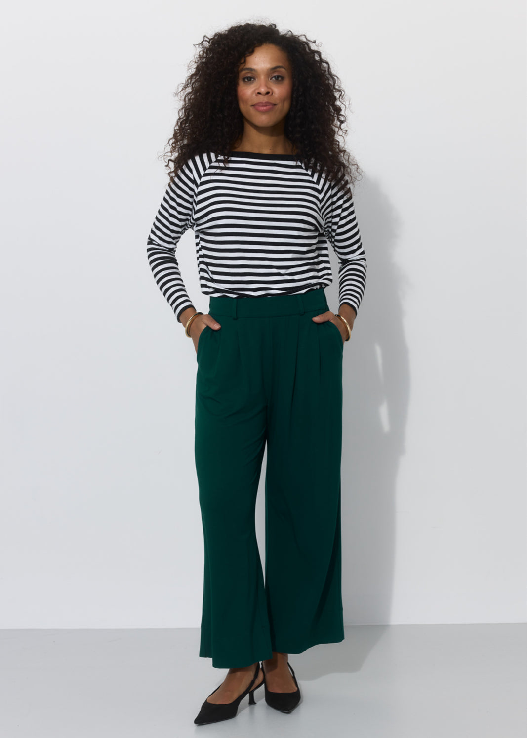 Kobieta w zielonych spodniach wide leg i koszulce w paski, stylowa i wygodna moda damska