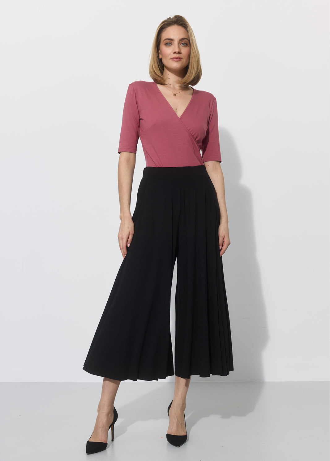 Różowa bluzka z dekoltem w szpic i czarne spodnie culotte – elegancka stylizacja na co dzień
