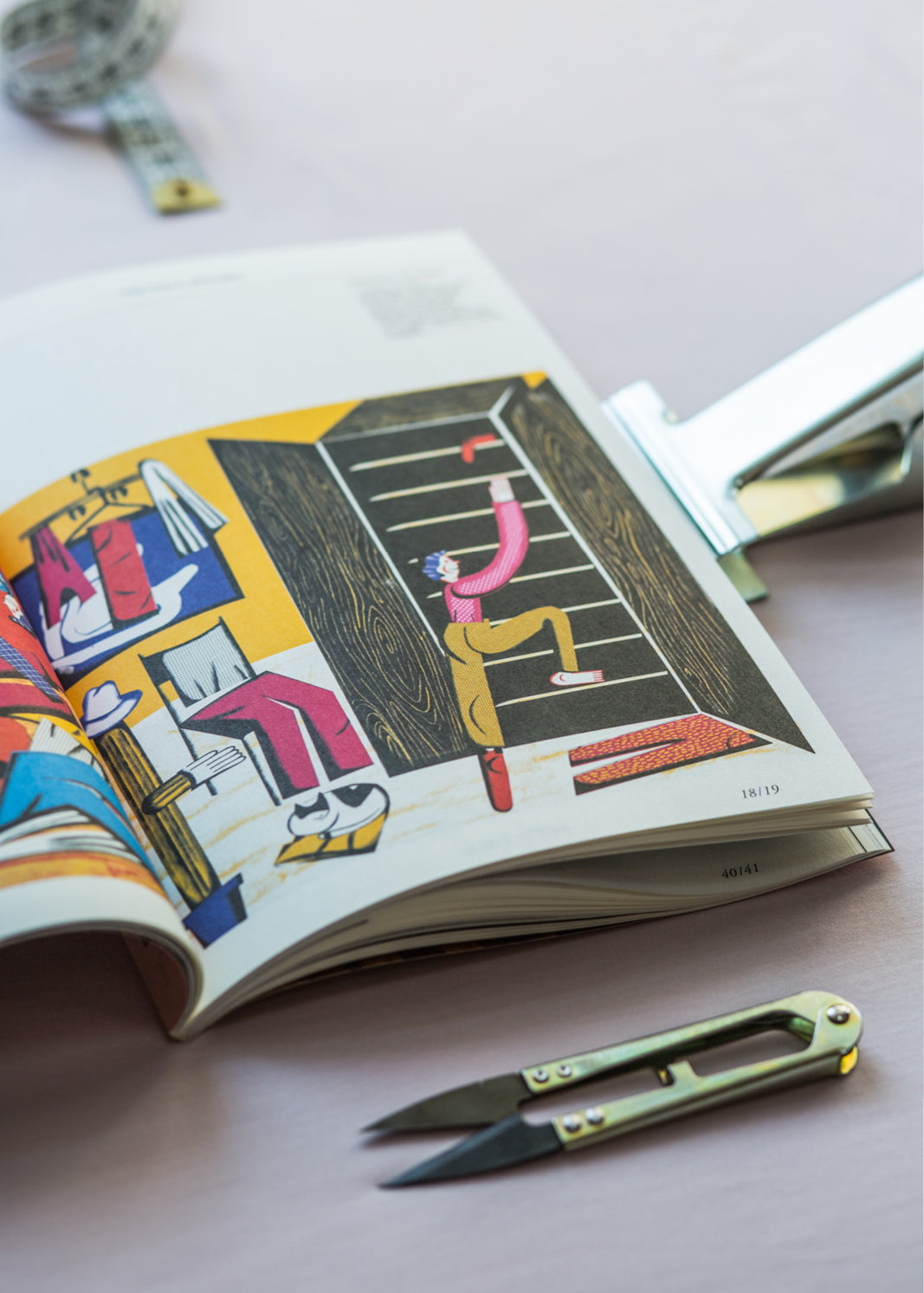 Książka z ilustracjami artystycznymi, miarka i nożyczki do szycia – inspiracja dla projektantów odzieży i miłośników mody.