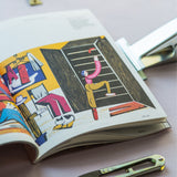 Książka z ilustracjami artystycznymi, miarka i nożyczki do szycia – inspiracja dla projektantów odzieży i miłośników mody.