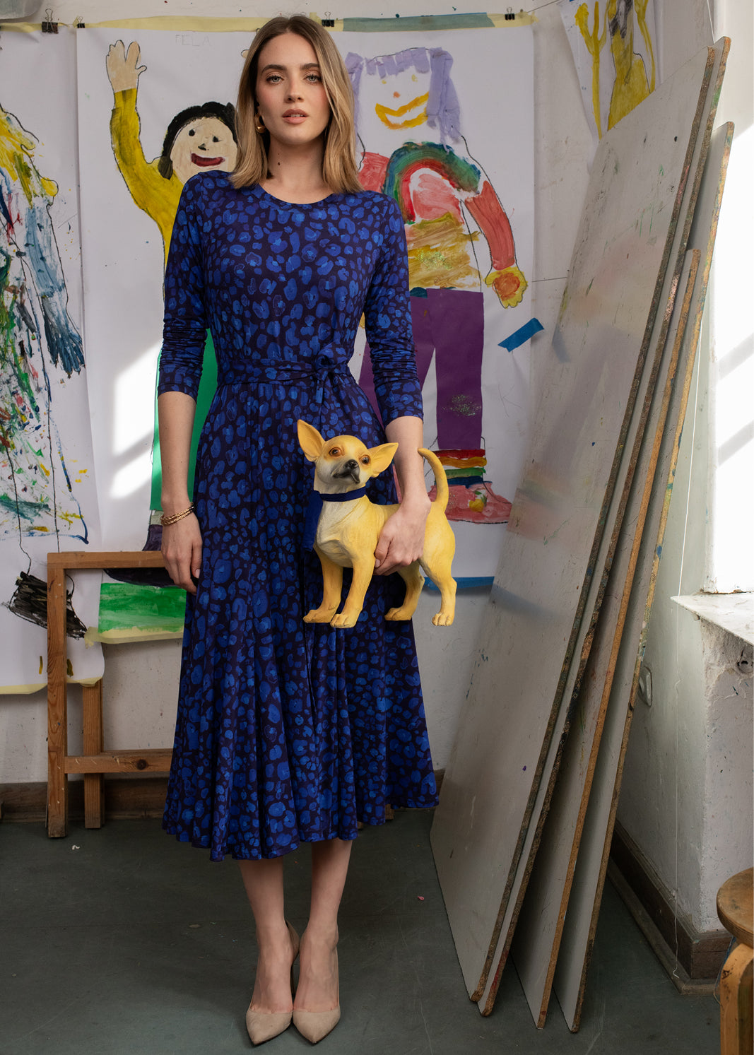 Kobieta w niebieskiej sukience w wzory z małym psem w artystycznym studio, moda polska, self-care fashion
