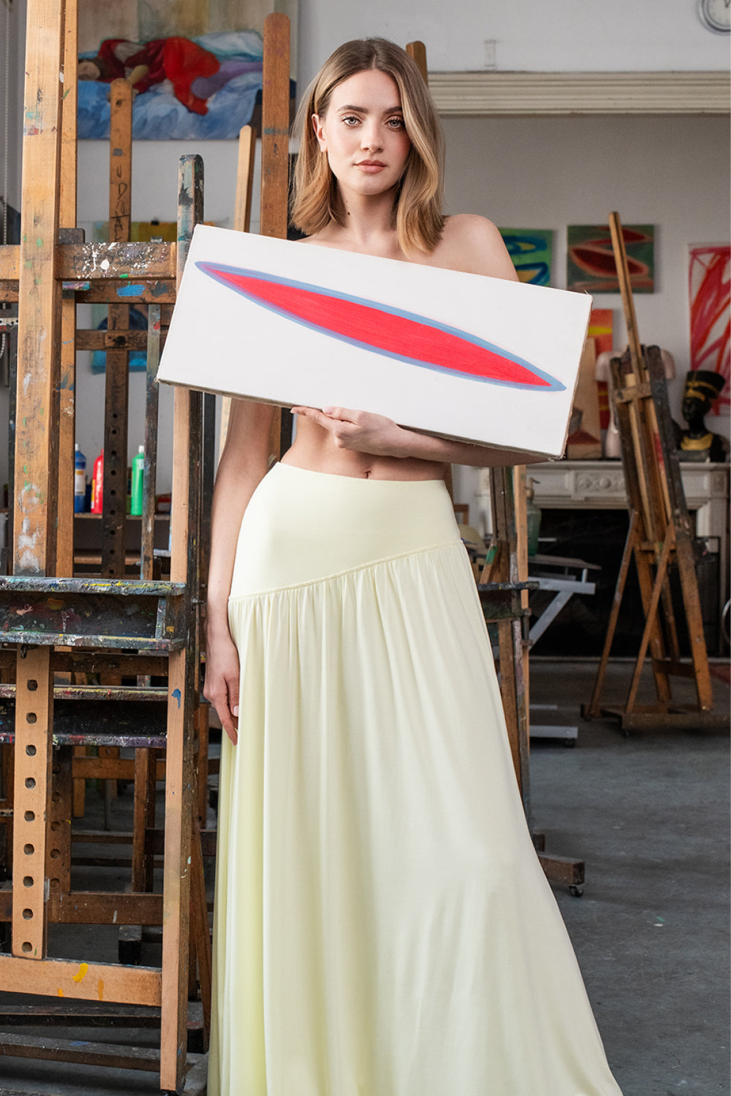Kobieta w kremowej, długiej spódnicy z sztuką w tle – elegancka, polska moda łącząca kulturę i wygodę.