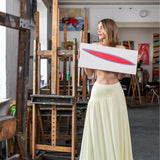Kobieta w żółtej sukience trzyma obraz w artystycznym atelier, stylowy i wygodny strój
