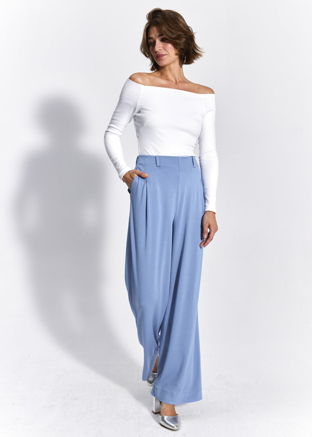 Błękitne spodnie oversize z białą bluzką off-shoulder, stylowa i wygodna stylizacja damska