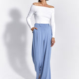 Błękitne spodnie oversize z białą bluzką off-shoulder, stylowa i wygodna stylizacja damska