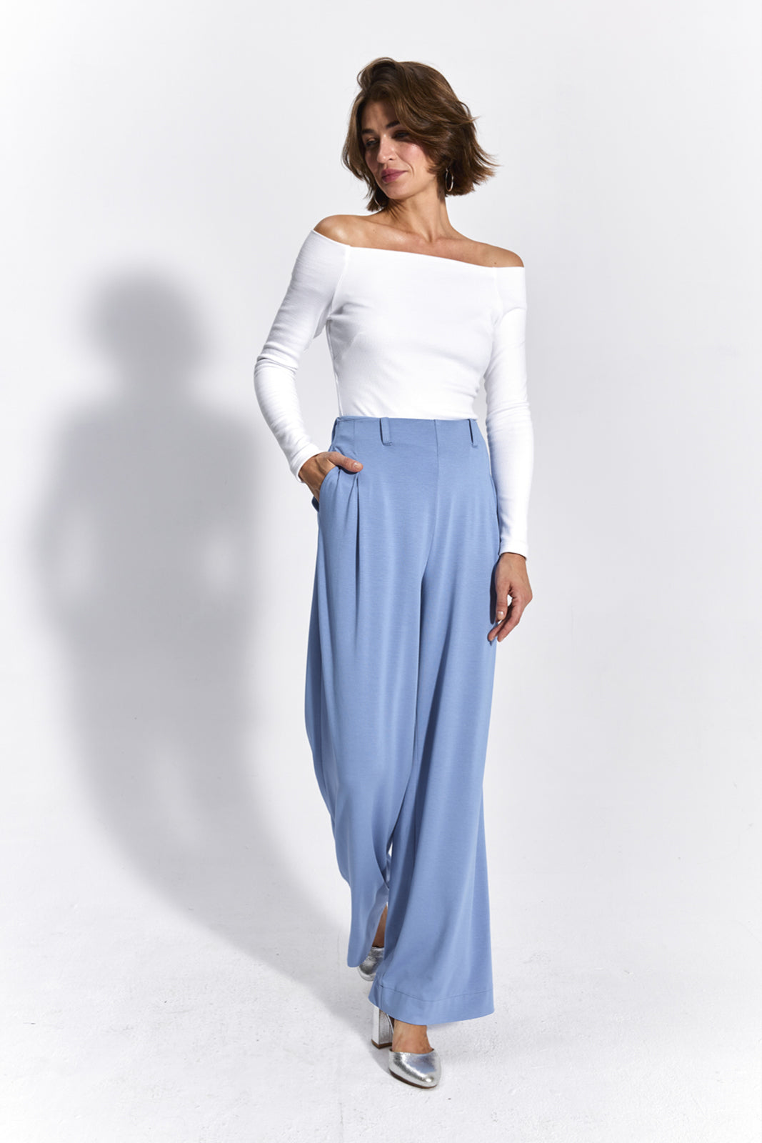 Błękitne spodnie oversize z białą bluzką off-shoulder, stylowa i wygodna stylizacja damska