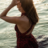 Kobieta w czerwonej sukience w wzór leopardi w wodzie, słońce odbija się na fali, stylowa i wygodna odzież
