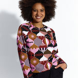 Kobieta w kolorowej bluzce z geometrycznym wzorem i czarnych spodniach, stylowa odzież damska