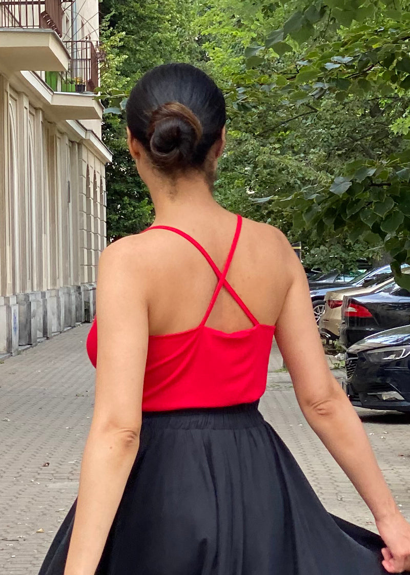 Czerwony top z krzyżowanymi ramiączkami i czarna spódnica w stylu self-care fashion, idealny na codzienne stylizacje.