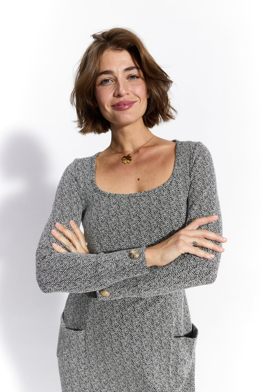 Kobieta w eleganckiej, szarej sukience z wzorem w paski, z kieszeniami i guzikami, idealna na codzienne stylizacje.