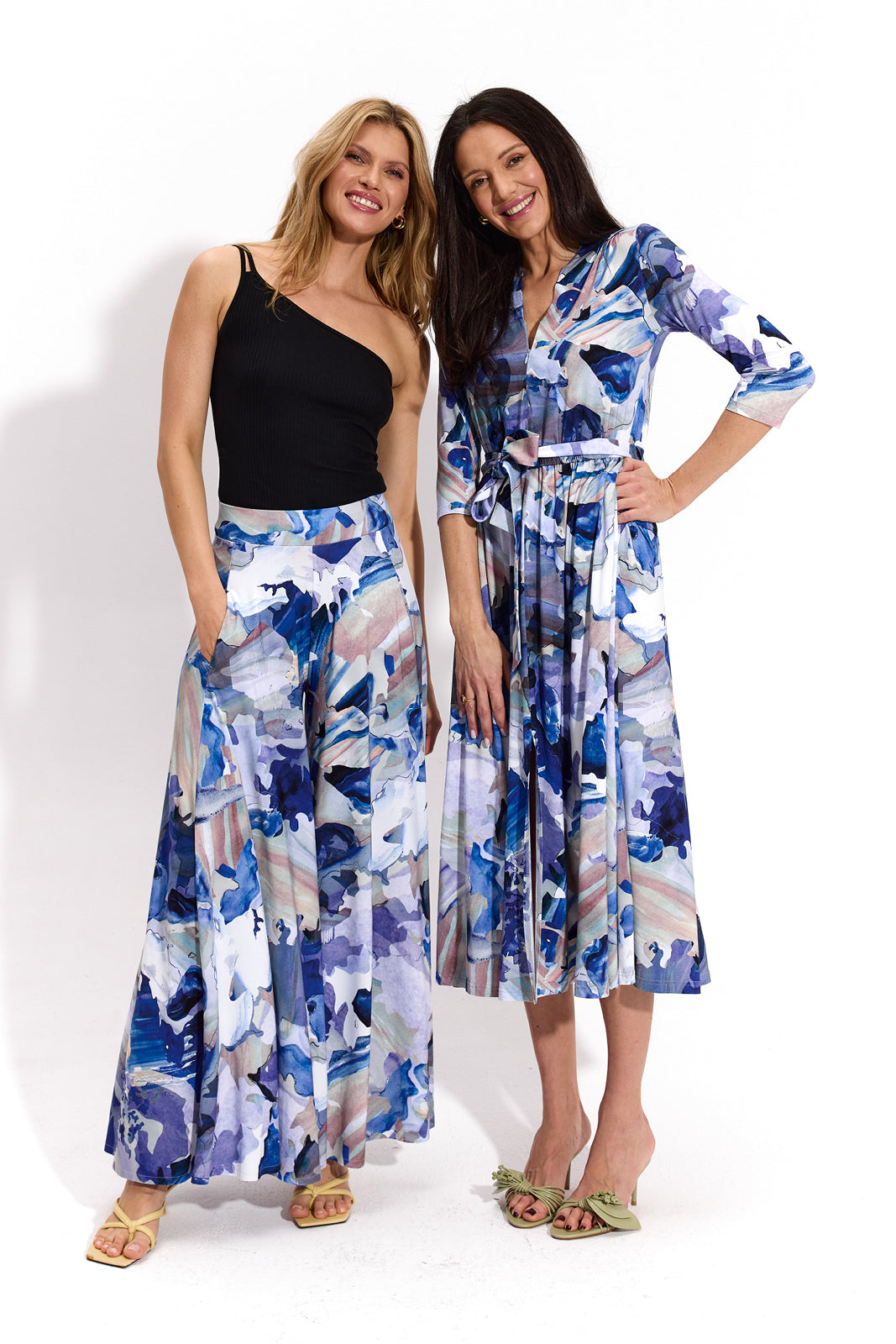 Dwie kobiety w modnych, kolorowych sukienkach i spodniach z abstrakcyjnym wzorem, idealne na letni styl i self-care fashion